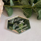 A hexagonal Destination Wedding Save The Date Magnet in mirror silver.The save the date has the wedding date and an aeroplane with a heart shaped trail behind engraved in to the acrylic.